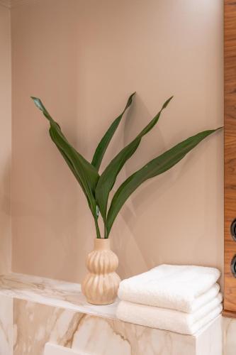 a vase with a plant on a shelf with towels at Queen's Court Hotel & Residence in Budapest
