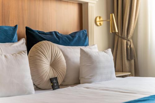 a bed with white pillows and a fan on it at Queen's Court Hotel & Residence in Budapest