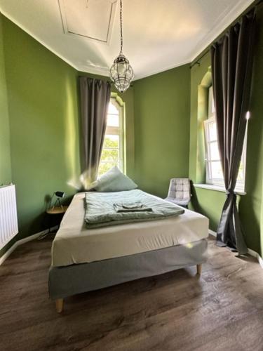 a bedroom with a bed with green walls and a window at Villa Blumenthal in Ludwigslust