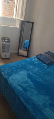 une chambre avec un lit bleu et un miroir dans l'établissement Charmant appartement de village, à Roquebrune-sur Argens