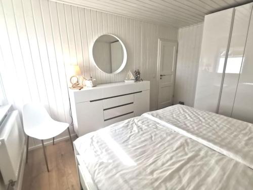 a white bedroom with a bed and a mirror at Hafenhaus Panoramablick mit Sauna & Whirlpool in Wandlitz
