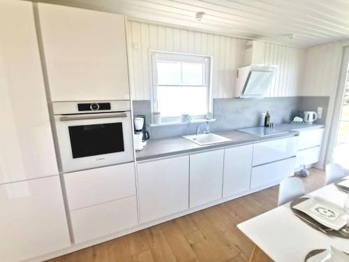 a white kitchen with a sink and a microwave at Hafenhaus Panoramablick mit Sauna & Whirlpool in Wandlitz
