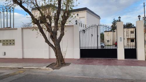 a tree in front of a white house with a gate at Hunuc apartamento in Rivadavia