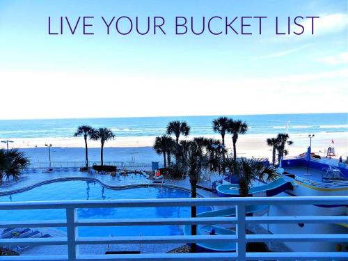 a sign that reads live your bucket list next to a beach at 6th Floor 1 BR Direct Oceanfront Condo Wyndham Ocean Walk - Daytona Funland 606 in Daytona Beach