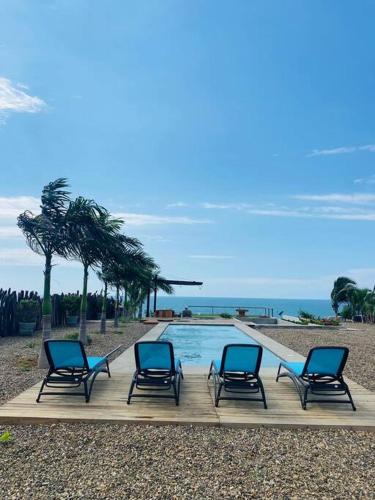 a group of four chairs sitting next to a pool at casaNorte paraíso norteño mirador de Ballenas in Canoas De Punta Sal