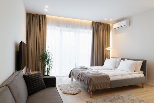 a bedroom with a bed and a couch in front of a window at ММ GROUP APARTMENT in Uzhhorod