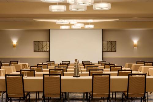a conference room with tables and chairs and a screen at Embassy Suites by Hilton Boston Waltham in Waltham