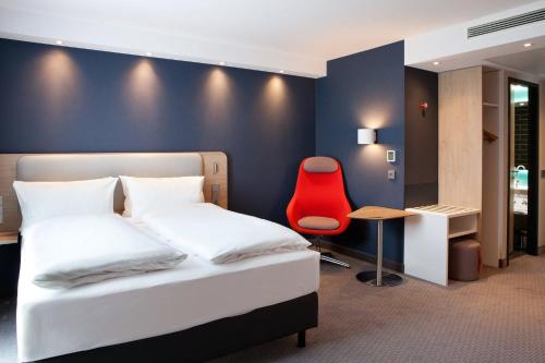 a bedroom with a bed and a red chair at Holiday Inn Express Munich - Olympiapark, an IHG Hotel in Munich