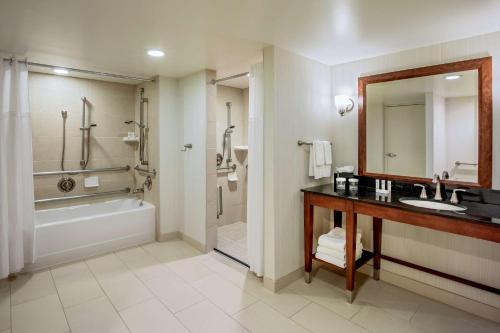 a bathroom with a sink and a tub and a mirror at Embassy Suites by Hilton Boston Waltham in Waltham
