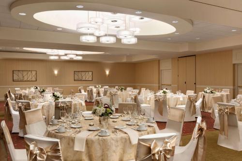 a banquet room with white tables and white chairs at Embassy Suites by Hilton Boston Waltham in Waltham