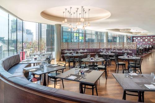 a restaurant with tables and chairs and windows at Hilton London Wembley in London