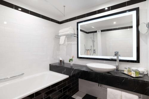 a bathroom with a sink and a tub and a mirror at Hilton London Wembley in London