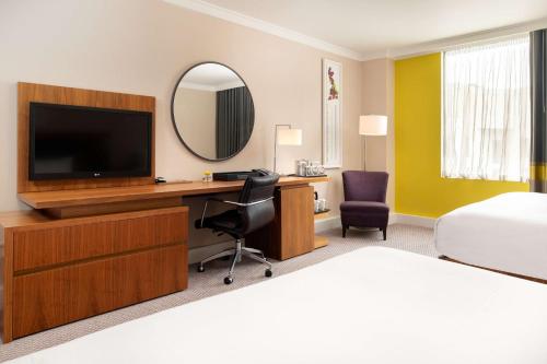 a hotel room with a desk with a television and a bed at Hilton London Wembley in London