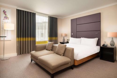 a hotel room with a bed and a chair at Hilton London Wembley in London