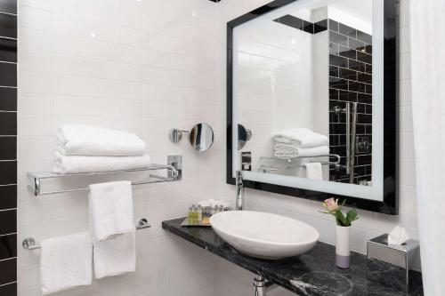 a white bathroom with a sink and a mirror at Hilton London Wembley in London