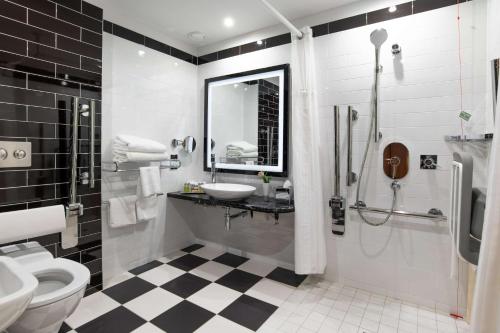 a bathroom with a black and white checkered floor at Hilton London Wembley in London