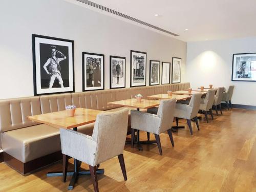 a restaurant with wooden tables and chairs and pictures on the wall at Hilton London Wembley in London