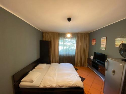 1 dormitorio con 1 cama blanca y TV en Lions Studio Dristor, en Bucarest