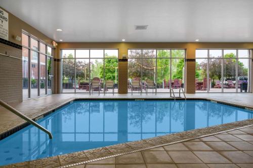a swimming pool in a hotel with windows and chairs at Wyndham Noblesville in Noblesville