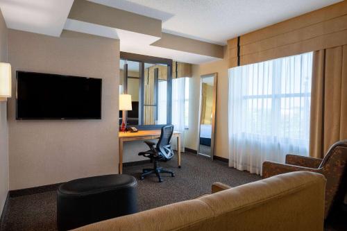 a hotel room with a couch and a desk with a television at Wyndham Noblesville in Noblesville