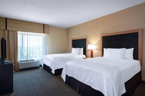 a hotel room with two beds and a television at Wyndham Noblesville in Noblesville