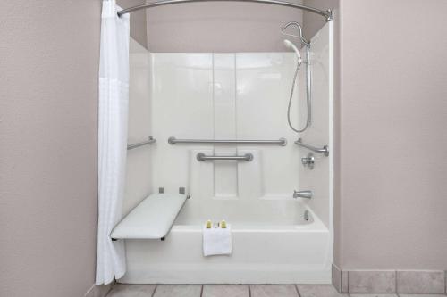 y baño con ducha y bañera blanca. en Super 8 by Wyndham New Braunfels I-35, en New Braunfels
