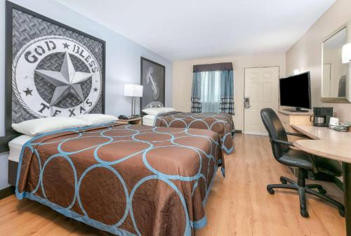 a hotel room with two beds and a desk at Super 8 by Wyndham New Braunfels I-35 in New Braunfels