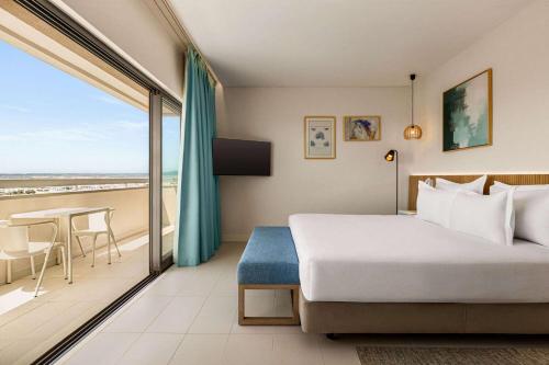 a bedroom with a bed and a balcony with a table at Wyndham Residences Alvor Beach in Alvor