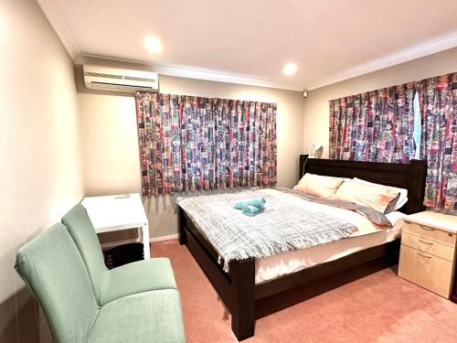 een kleine slaapkamer met een bed en een stoel bij West Harbour White House (西港白宫） in Auckland