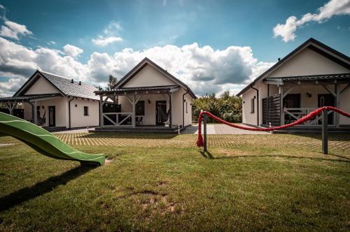 a yard with a slide in front of two houses at Domki Pod Dębem in Sulęczyno