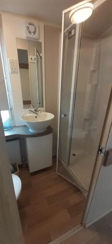 a bathroom with a glass shower and a sink at Arual Caravan Manor House Park. Allonby, Cumbria in Maryport