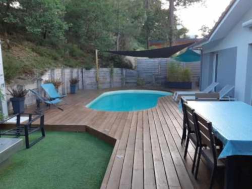 een achtertuin met een zwembad en een houten terras bij Jolie maison moderne et sereine à Labenne in Labenne