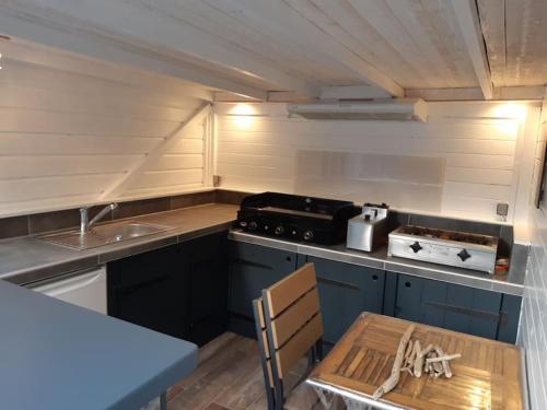 een kleine keuken met blauwe kasten en een wastafel bij Jolie maison moderne et sereine à Labenne in Labenne