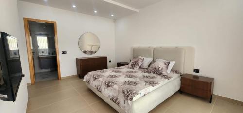 a bedroom with a large bed and a mirror at Villa fadhloun 2 in Awlād ‘Umar