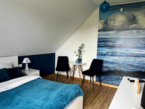 a bedroom with a bed and a painting of the ocean at Bałtyckie Klimaty in Stegna