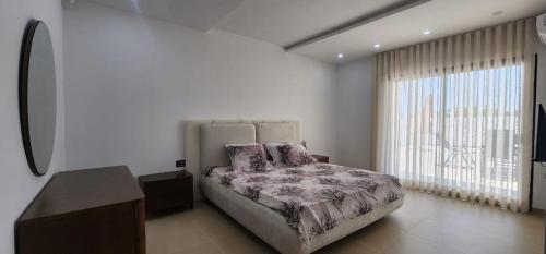 a bedroom with a bed and a large window at Villa fadhloun 2 in Awlād ‘Umar