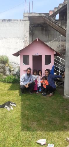 a group of people sitting in front of a pink house at Casa Apartamento Campestre en las Faldas del Tayta Imbabura in San Juan de Ilumán