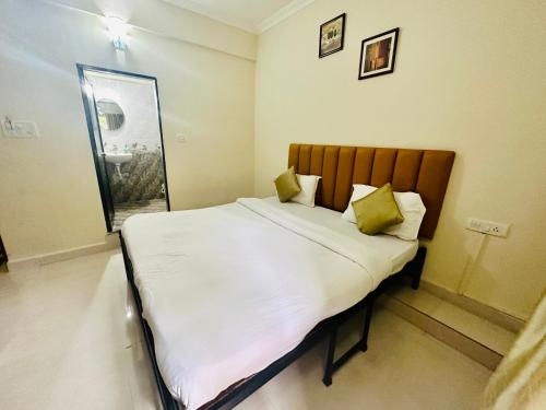 a bedroom with a white bed with yellow pillows at Hotel Leela Inn Candolim in Marmagao