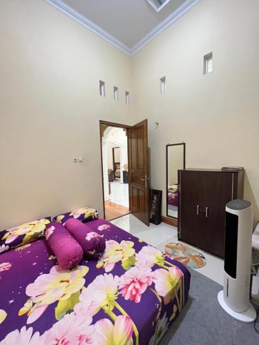 Un dormitorio con una cama púrpura con flores. en Guesthouse Eldys, en Gondowulung