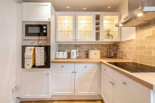 a white kitchen with white cabinets and appliances at Something a little bit special! in Llandudno