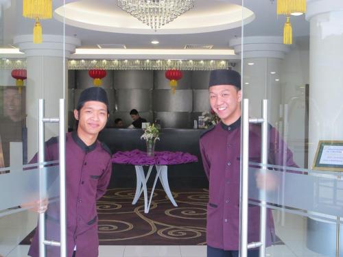 two men in purple uniforms standing in a restaurant at Badi'ah Hotel in Bandar Seri Begawan