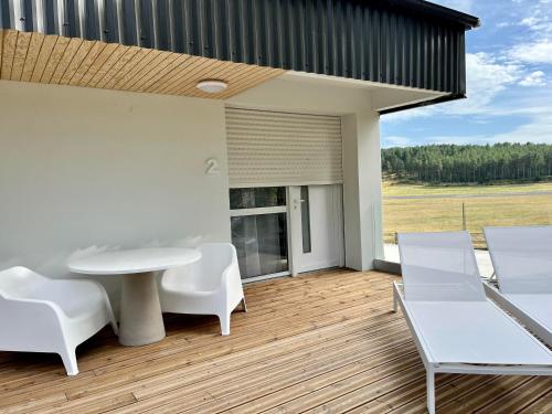 d'une terrasse avec une table et des chaises blanches. dans l'établissement Domaine de Mende Brenoux Suites & SPA, à Mende
