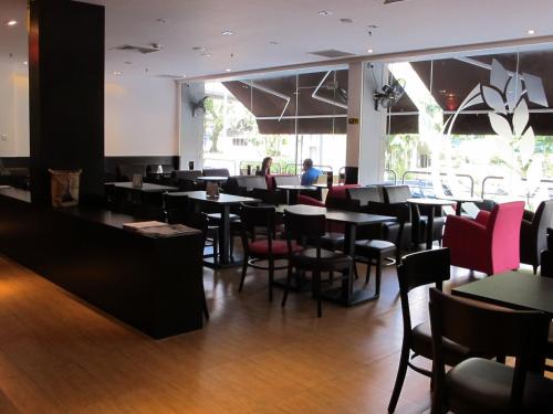 a restaurant with tables and chairs and a person in the background at Badi'ah Hotel in Bandar Seri Begawan