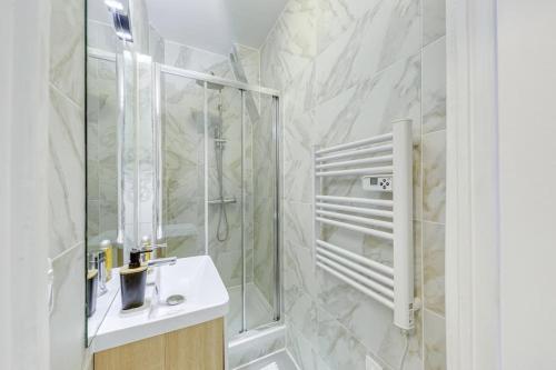a bathroom with a shower and a sink and a mirror at Appartement Moderne, proche Porte de Versailles et Gare de Clamart in Malakoff