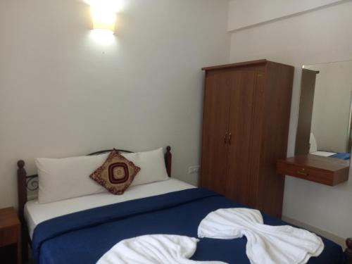 1 dormitorio con 1 cama y armario de madera en Sea Mist Apartment, en Candolim