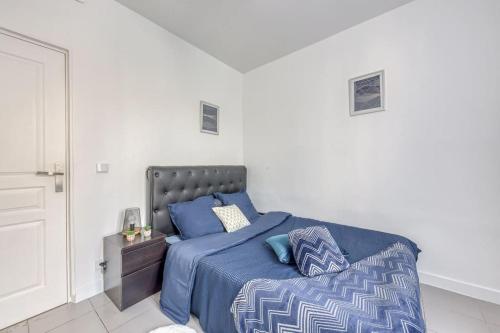 a bedroom with a bed with a blue comforter at Appartement Moderne, proche Porte de Versailles et Gare de Clamart in Malakoff