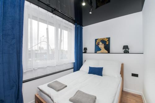 Schlafzimmer mit einem Bett mit blauen Vorhängen und einem Fenster in der Unterkunft Apartament Jagielońska 1/3 in Gliwice