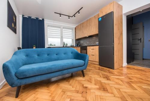 ein blaues Sofa im Wohnzimmer mit Küche in der Unterkunft Apartament Jagielońska 1/3 in Gliwice
