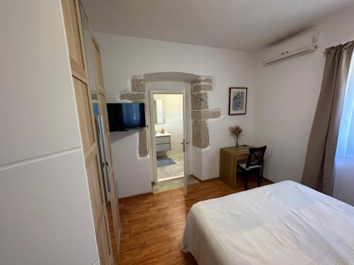 1 dormitorio con 1 cama y TV en la pared en Božini dvori, en Drniš