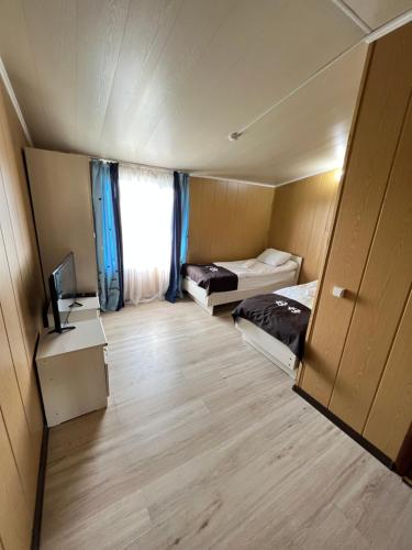 Habitación pequeña con 2 camas y TV. en Sanjyra hostel, en Karakol